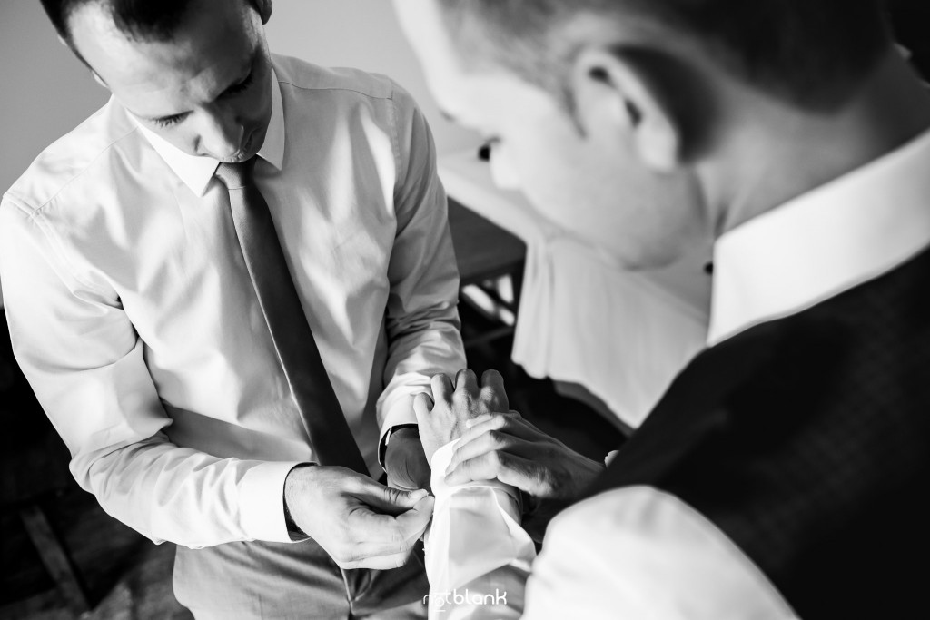 Boda en el Parador de Baiona realizado por Notblank fotografos de boda - El primo del novio le coloca los gemelos al novio