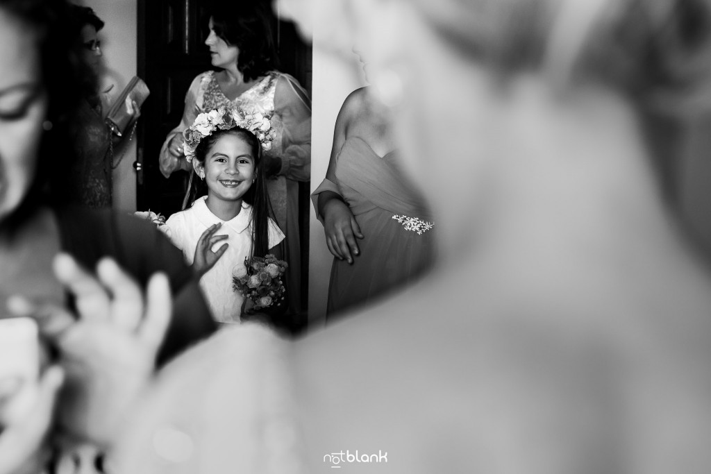 Boda en el Parador de Baiona realizado por Notblank fotografos de boda - La niña de arras sonrie a la novia