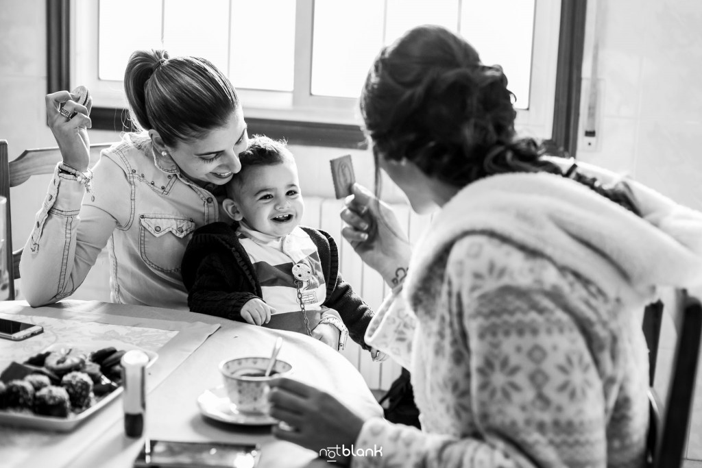 Boda en Salceda de Caselas. La novia se toma un café durante los preparativos junto a una amiga y al hijo pequeño de esta. Reportaje realizado por Notblank fotógrafos de boda en Galicia.