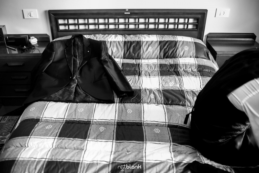 Boda en Salceda de Caselas. El novio está sentado encima de la cama colocándose los zapatos. Reportaje realizado por Notblank fotógrafos de boda en Galicia.