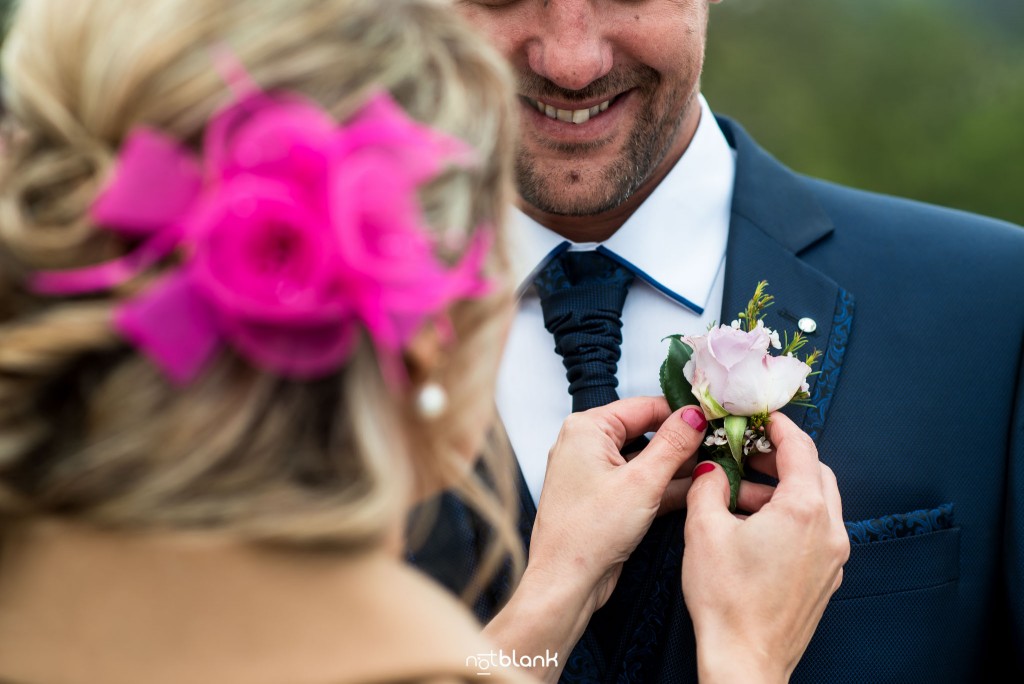 Boda en Salceda de Caselas. Una amiga del novio le coloca el botonier al novio. Reportaje realizado por Notblank fotógrafos de boda en Galicia.