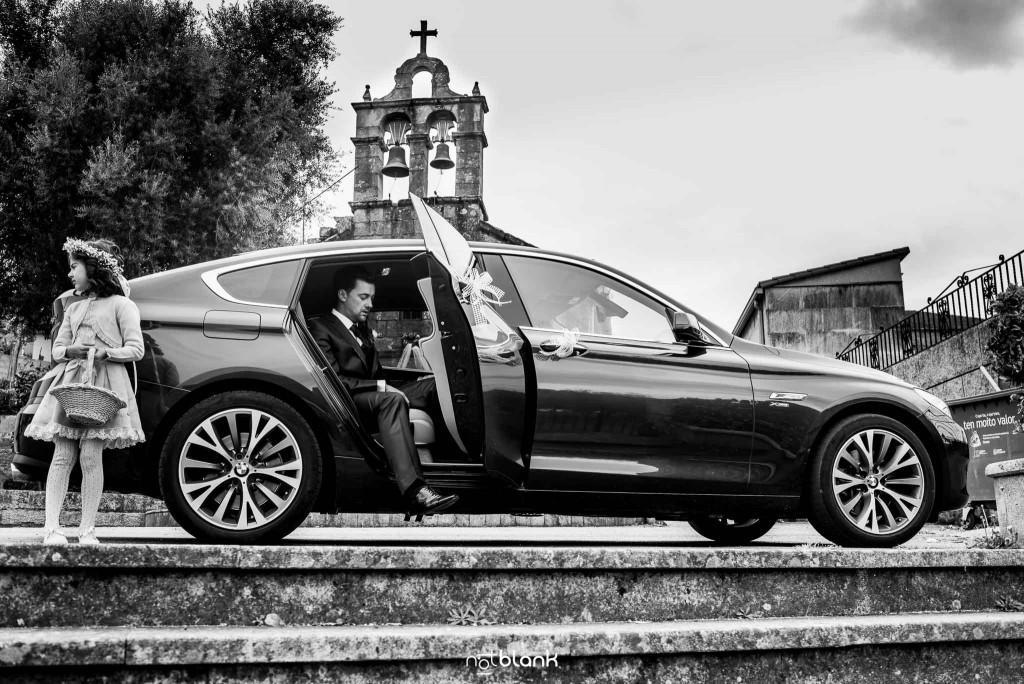 Boda en Salceda de Caselas. El novio se baja de un BMW al llegar a la iglesia. Reportaje realizado por Notblank fotógrafos de boda en Galicia.