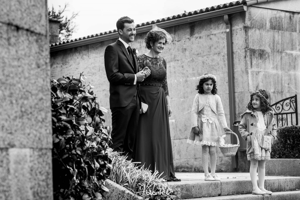 Boda en Salceda de Caselas. El novio ya su madre reciben a los invitados a la puerta de la iglesia. Reportaje realizado por Notblank fotógrafos de boda en Galicia.