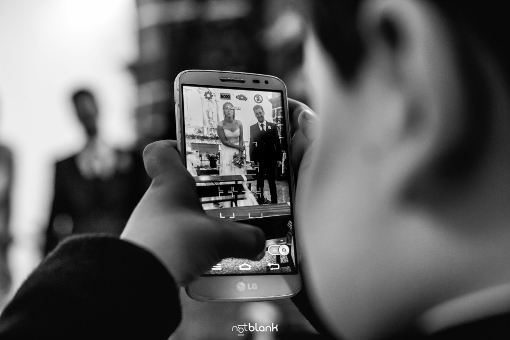 Boda en Salceda de Caselas. Un niño invitado a la boda quita una foto con un móvil a los novios en la iglesia. Reportaje realizado por Notblank fotógrafos de boda en Galicia.