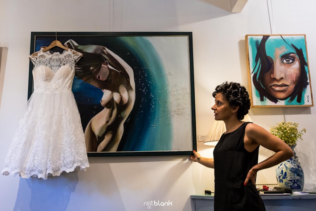 Boda en Quinta San Amaro en Meaño. La novia mira atentamente para su precioso vestido colgado de un oleo en la pared. Reportaje realizado por Notblank fotógrafos de boda en Cangas.