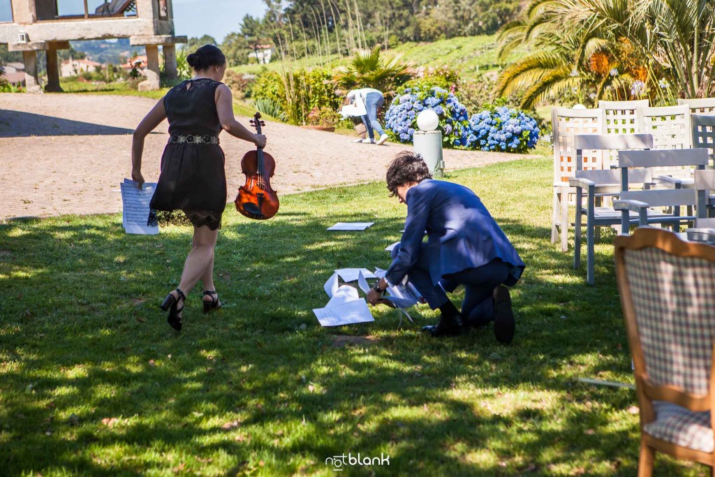 Boda en Quinta San Amaro en Meaño. El sobrino de la novia ayuda a la violinista a recoger las partituras que han salido volando debido al viento. Reportaje realizado por Notblank fotógrafos de boda en Cangas.