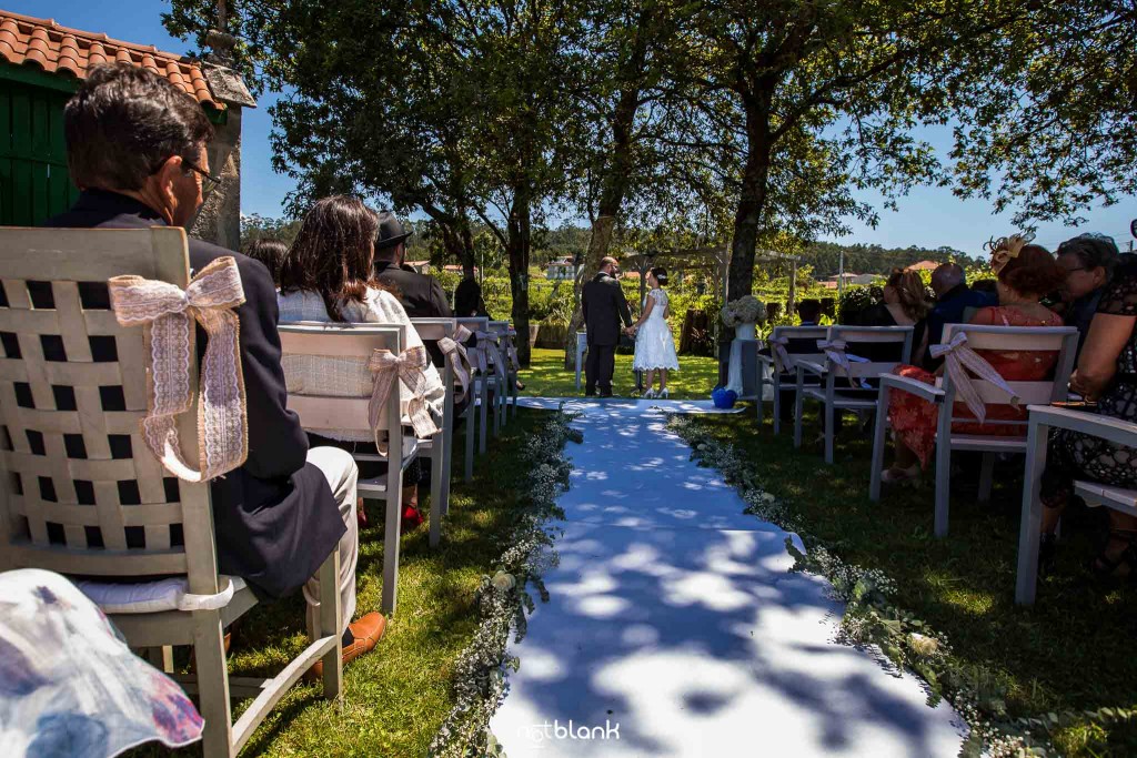 Boda en Quinta San Amaro en Meaño. Los novios están en el altar y los invitados los observan. Reportaje realizado por Notblank fotógrafos de boda en Cangas.