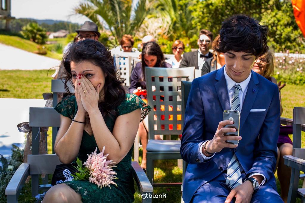 Boda en Quinta San Amaro en Meaño. La hermana de la novia se emociona y llora durante la ceremonia civil. El sobrino de la novia graba con su teléfono móvil la ceremonia. Reportaje realizado por Notblank fotógrafos de boda en Cangas.