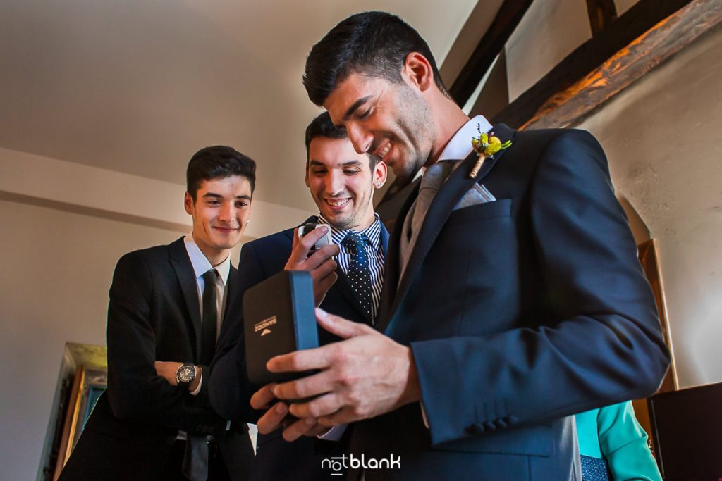 El novio junto a sus hermanos mira el reloj que le ha regalado su novia