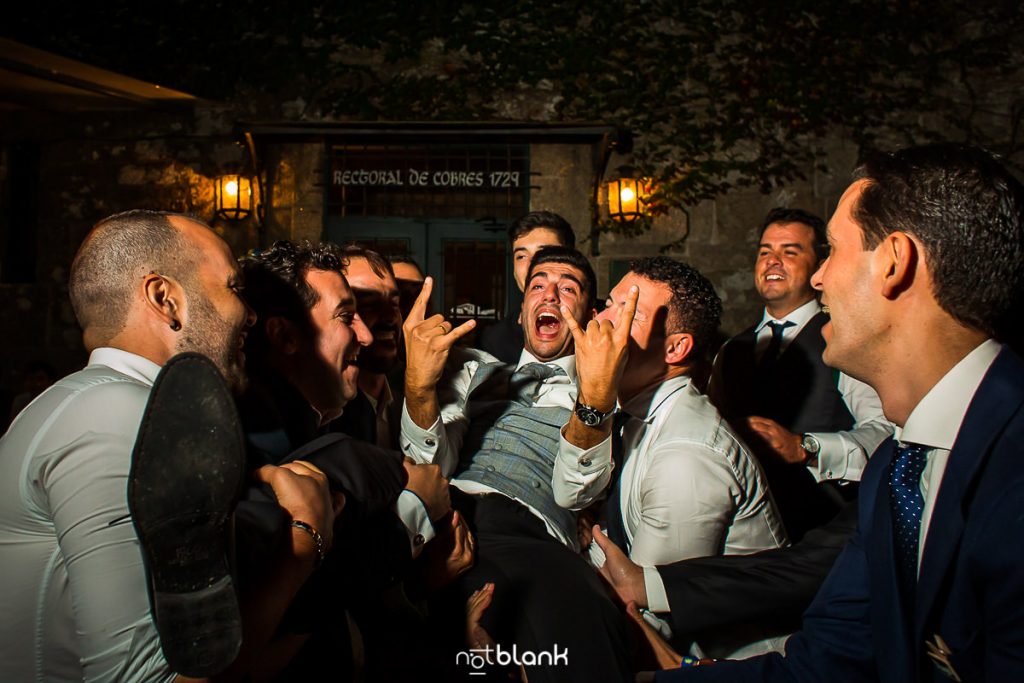 Los amigos de los novios aúpan al novio durante la fiesta