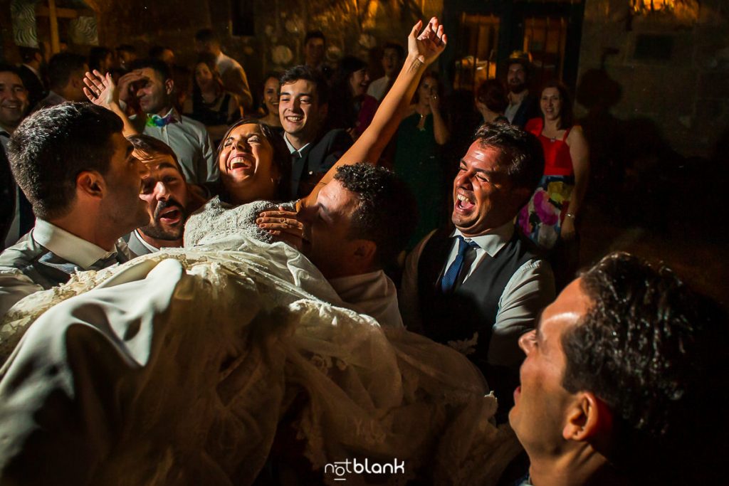 Los amigos de los novios aúpan a la novia durante la fiesta